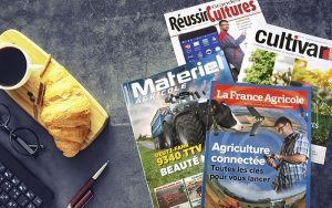 Rechts auf dem Bild sind vier Zeitschriften der Ausgaben La France Agricole, Matériel Agrocile, Cultivar und Réussir Grandes Cultures zu sehen. Links auf dem Bild liegt ein Holzbrett mit einer Kaffeetasse und einem Croissant drauf. Links unten in der Ecke sieht man den Anschnitt einer Computertastatur und eines Stifts.